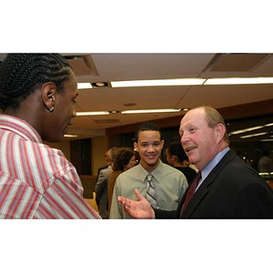 Ted English converses with two students at the Torch Scholars dinner