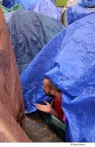 Occupy Wall Street: man reaching out of a tent, testing for rain