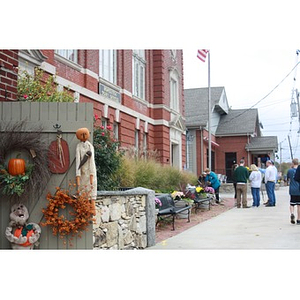 Volunteers stand in background in front of fall-decorated building