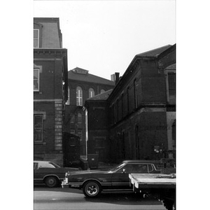 View of the alleyway between La Alianza Hispana's headquarters, 409 Dudley Street (building on left) and 407 Dudley Street (on right), taken from across the street; there are cars driving by in the foreground.