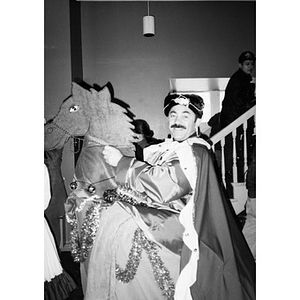 Man dressed as one of the Magi riding a fake horse.