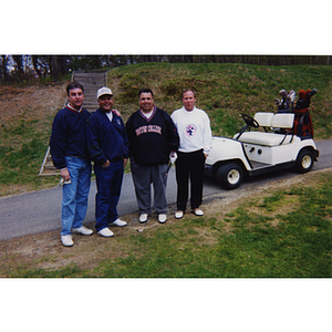 A four-man golf team posing in front of a golf cart at the Charlestown Boys and Girls Club Annual Golf Tournament