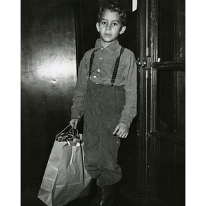 A boy carries Christmas gifts in a paper bag