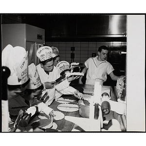 Members of the Tom Pappas Chefs' Club frost cakes under the guidance of a kitchen staff member