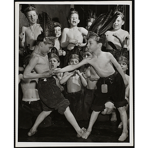 Two boys wrestling each other in front of cheering boys