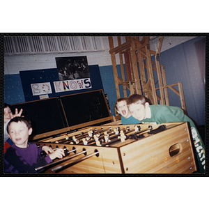 Four boys pose for a candid shot while playing foosball