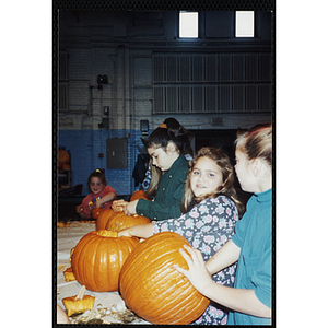 Three girls carve pumpkins at a Halloween event