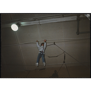 A girl walks across a gymnasium on a rope