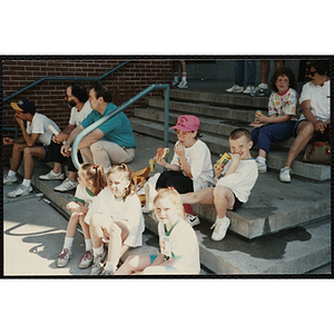 Children and adults sit on steps at the Battle of Bunker Hill Road Race