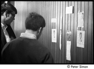Students reading newsclippings posted on the wall : Vietnam War sanctuary at MIT