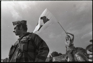 Antiwar demonstration at Fort Dix, N.J.: man in foreground wearing Vets for Peace in Vietnam hat, woman in background waving flag for draft resistance (with omega symbol)