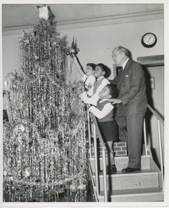 Jeremiah Milbank, Sr. decorating Christmas tree with three young client