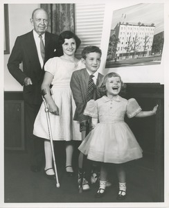 Jeremiah Milbank and three children standing in front of a picture of the new ICD building