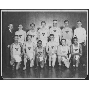 Group portrait of track team with coaches inside gym