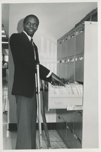 Man with crutches filing documents