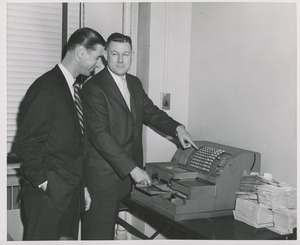 Two men looking at a cash register during an administrators' training event