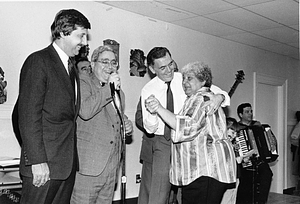 Mayor Raymond L. Flynn dances with an unidentified woman as his daughter Katie sings along and John Rampino plays accordion