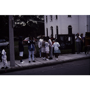 Crowd of onlookers standing on a sidewalk