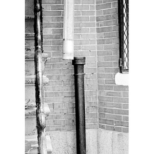 Drain pipe hanging alongside a set of stone steps.