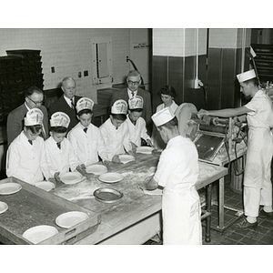 Members of the Tom Pappas Chefs' Club prepare pie shells with staff in a kitchen