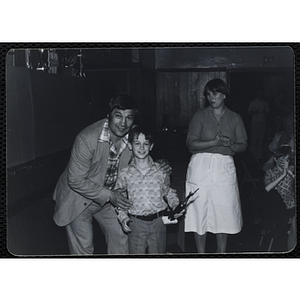 A man and a boy with his trophy posing as a woman looks on from behind during a Boys' Clubs of Boston Awards Night