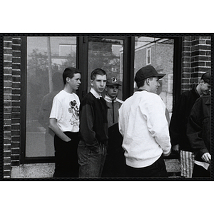 Several teenage boys gather in front of a window outside the Charlestown Boys & Girls Club building