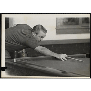 An older man lines up his shot at a pool table