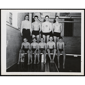 A swim team of boys and teenage boys pose for a group shot with thier coach