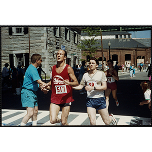 Runners crossing the finish line are congratulated by a race official during the Battle of Bunker Hill Road Race