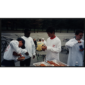 Boys prepare hotdogs in a parking lot at The Partnership Ride