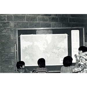 Three children and a teenager look at a map of "China's relations with other countries in the world" in the lobby of the Josiah Quincy School before attending a program about the normalization of U.S. and China relations