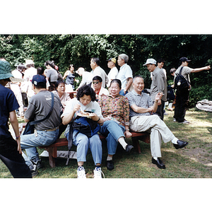 Men and women eat and converse in a picnic area