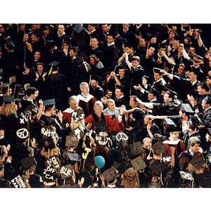 President Bill Clinton, speaker at 1993 June commencement, shakes hands as he processes through a sea of graduates