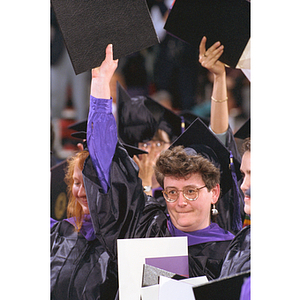 Students wave their diplomas during commencement ceremony