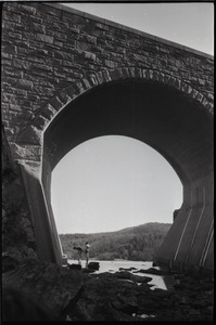 Two men standing in arch beneath an aqueduct (?)