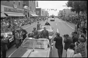 Robert F. Kennedy and Walter Mondale riding in a convertible down the streets of Worthington during the Turkey Day festivities (a giant turkey float looms in the background)