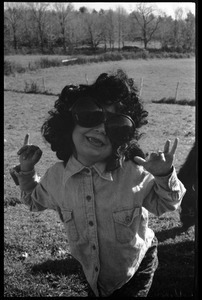 Young girl playing dress up with a wig and dark glasses, Montague Farm Commune