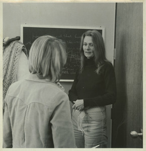 Joan P. Bean standing indoors, talking to student