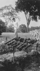 Richard M. Brown basting at a barbecue pit, summer session barbecue