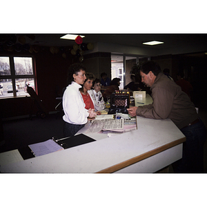 Man speaking to three women at front desk