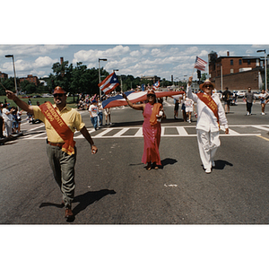 The President and Grand Marshal of the Festival Puertorriqueño parade march together with a woman