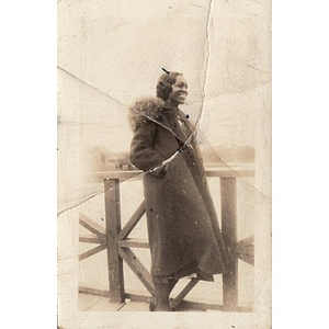 A woman leans against a wooden railing