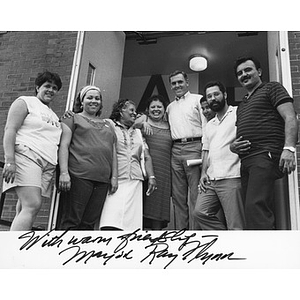 Mayor Ray Flynn (standing fifth from left) outside a brick building, with a group of four women and three Latino men, at a political event.
