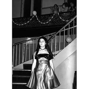 Teenage girl in a party dress standing at the foot of the spiral staircase in the Jorge Hernandez Cultural Center.