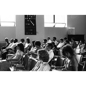 Unidentified people sitting in a large classroom or auditorium listening to speakers at the front of the room.