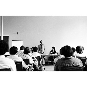 Unidentified man addressing a room full of people.