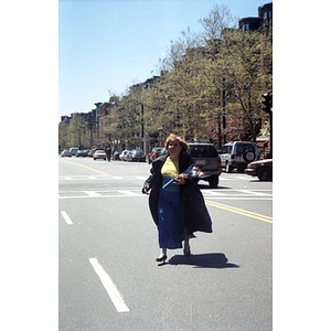 Woman with a bouquet of flowers crosses the street.