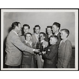 A man presents a trophy to a Boys' Club basketball team