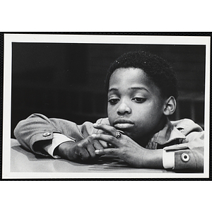 An African American boy from the Boys' Clubs of Boston sitting with his arms on the table