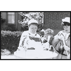 A woman making a cotton candy while two others stand beside her at the Boys and Girls Clubs of Boston 100th Anniversary Celebration Street Fair